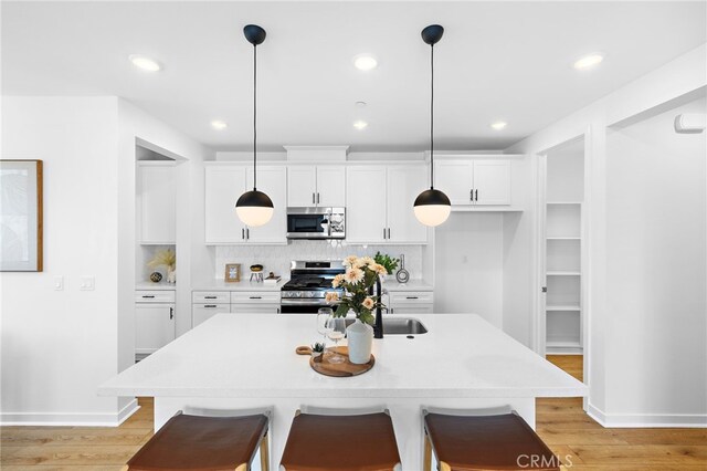 944 N Divino Privado Unit 57, Ontario, CA 91764 - kitchen featuring appliances with stainless steel finishes, white cabinets, backsplash, light wood-style floors, and recessed lighting