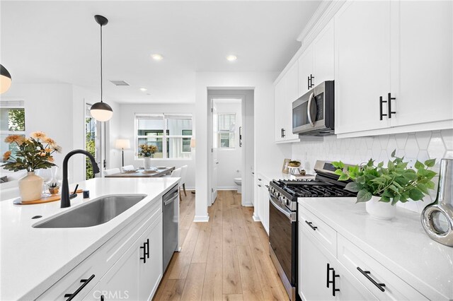 944 N Divino Privado Unit 57, Ontario, CA 91764 - kitchen featuring stainless steel appliances, tasteful backsplash, light wood-type flooring, white cabinetry, and light countertops