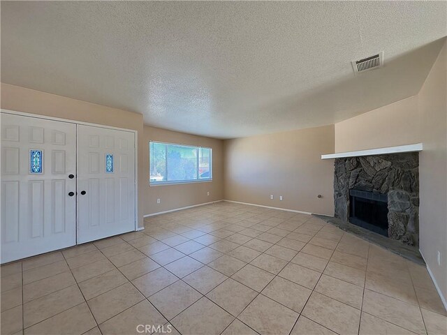 22241 Cholena Rd, Apple Valley, CA 92307 - unfurnished living room featuring light tile patterned flooring, a textured ceiling, and a stone fireplace