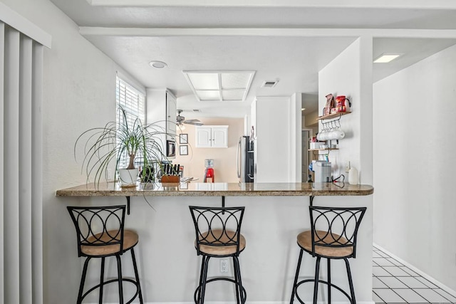 3428 Cameo Dr # 49, Oceanside, CA 92056 - kitchen featuring freestanding refrigerator, white cabinetry, a kitchen bar, and a peninsula