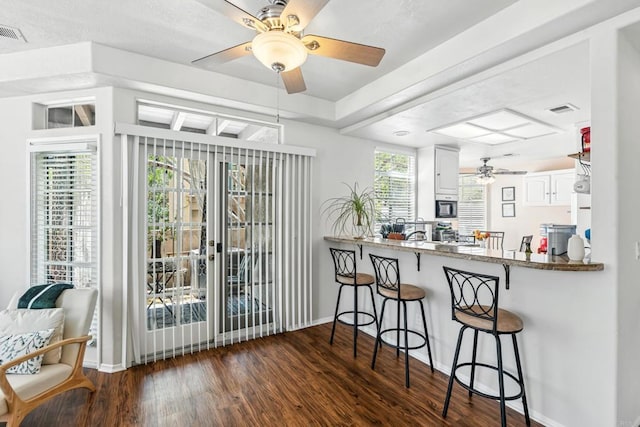3428 Cameo Dr # 49, Oceanside, CA 92056 - kitchen featuring ceiling fan, built in microwave, dark wood-style floors, a breakfast bar area, and white cabinets