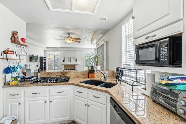 3428 Cameo Dr # 49, Oceanside, CA 92056 - kitchen with black appliances, a fireplace, a ceiling fan, white cabinets, and light stone counters