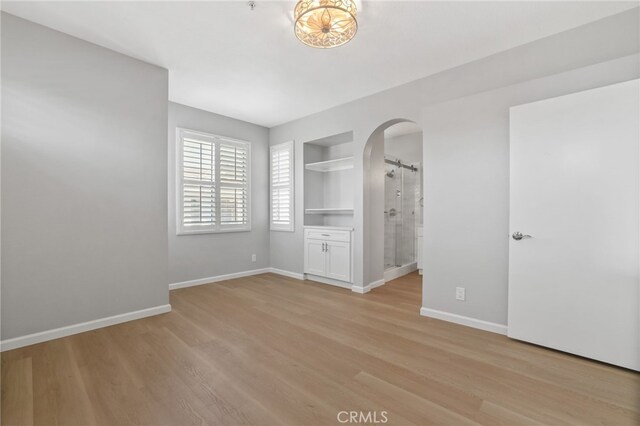 41 Breakers Ln, Aliso Viejo, CA 92656 - spare room with arched walkways, light wood finished floors, built in shelves, and a barn door