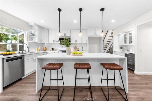 11685 Lakia Dr, Cypress, CA 90630 - kitchen featuring stainless steel appliances, beverage cooler, white cabinets, open shelves, and a center island