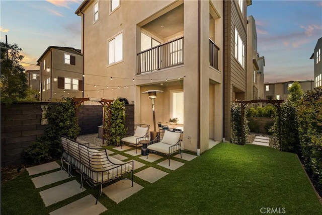 1281 Windmill Rd, Rancho Mission Viejo, CA 92694 - back of property at dusk with a balcony, a patio, stucco siding, and a fenced backyard