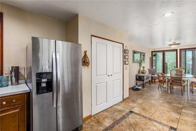 30421 Live Oak Dr, Running Springs, CA 92382 - kitchen featuring stainless steel refrigerator with ice dispenser, light countertops, brown cabinets, and inlaid floor details