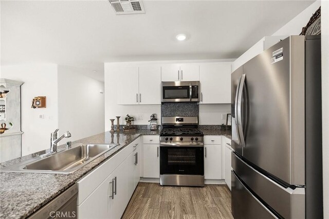 1943 Auger Pl, Hemet, CA 92545 - kitchen with appliances with stainless steel finishes, white cabinets, wood finished floors, a peninsula, and recessed lighting
