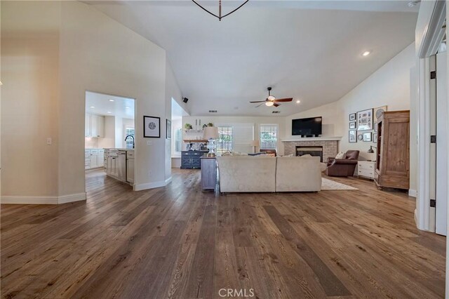 770 Warbler Ct, Merced, CA 95340 - living room with dark wood-style flooring, ceiling fan, a brick fireplace, high vaulted ceiling, and recessed lighting