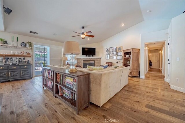 770 Warbler Ct, Merced, CA 95340 - living area with light wood-style floors, ceiling fan, lofted ceiling, and a brick fireplace