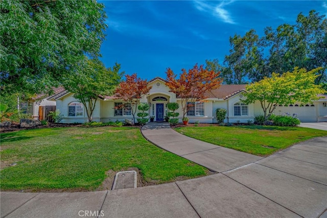 770 Warbler Ct, Merced, CA 95340 - view of front of home with stucco siding, a front lawn, a tile roof, and an attached garage