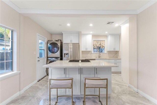 19119 Lemay St, Reseda, CA 91335 - kitchen featuring appliances with stainless steel finishes, stacked washer / dryer, a kitchen island, white cabinetry, and a breakfast bar