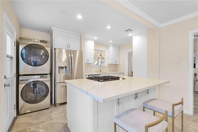19119 Lemay St, Reseda, CA 91335 - kitchen featuring estacked washer and dryer, appliances with stainless steel finishes, a kitchen island, white cabinets, and light stone countertops