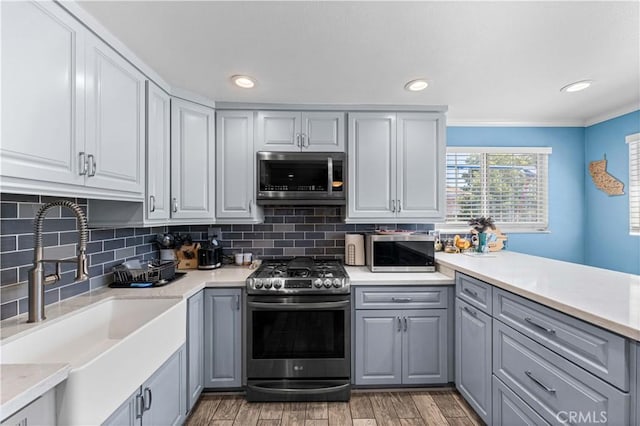 42545 30th St W, Lancaster, CA 93536 - kitchen with stainless steel appliances, gray cabinetry, light wood-style floors, backsplash, and crown molding