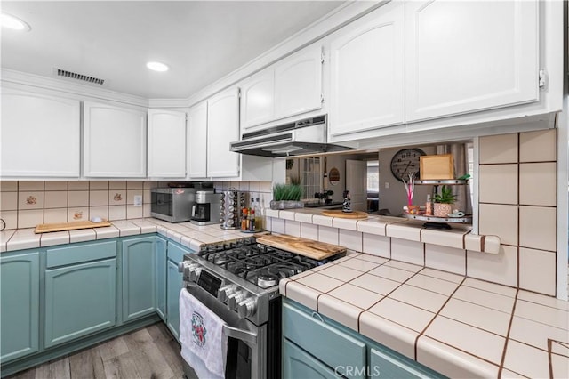 42545 30th St W, Lancaster, CA 93536 - kitchen featuring stainless steel appliances, under cabinet range hood, white cabinetry, tile counters, and recessed lighting