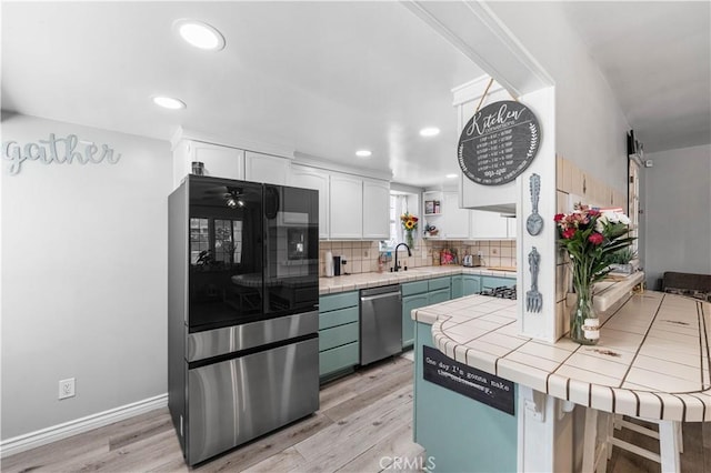 42545 30th St W, Lancaster, CA 93536 - kitchen with smart refrigerator, tile counters, white cabinetry, stainless steel dishwasher, and light wood finished floors