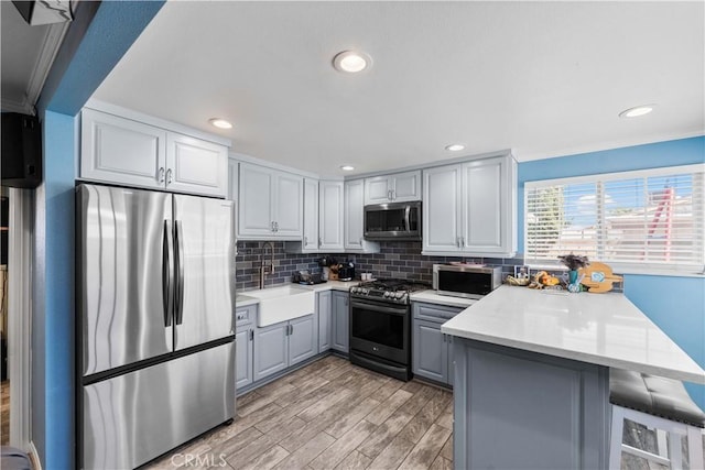 42545 30th St W, Lancaster, CA 93536 - kitchen with stainless steel appliances, gray cabinetry, a peninsula, tasteful backsplash, and a breakfast bar area