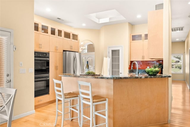 13962 Lindbergh Cir, Chico, CA 95973 - kitchen featuring freestanding refrigerator, light brown cabinetry, dark stone countertops, a peninsula, and light wood-style floors