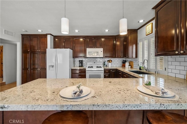 21643 Masterson Ct, Saugus, CA 91350 - kitchen featuring white appliances, decorative backsplash, light stone countertops, dark brown cabinetry, and recessed lighting