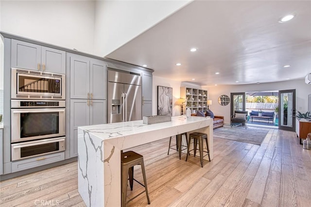 2008 Baja, Newport Beach, CA 92660 - kitchen featuring built in appliances, gray cabinets, open floor plan, light stone countertops, and light wood-style floors