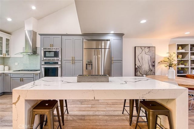 2008 Baja, Newport Beach, CA 92660 - kitchen with gray cabinetry, appliances with stainless steel finishes, wall chimney exhaust hood, backsplash, and a breakfast bar area