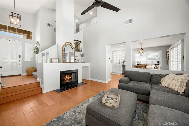 870 Clover Ln, Corona, CA 92878 - living room featuring wood finished floors, a towering ceiling, a ceiling fan, a glass covered fireplace, and recessed lighting