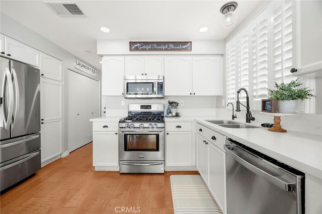 870 Clover Ln, Corona, CA 92878 - kitchen with appliances with stainless steel finishes, white cabinetry, light wood finished floors, light countertops, and recessed lighting