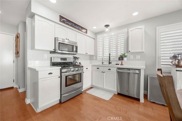 870 Clover Ln, Corona, CA 92878 - kitchen with appliances with stainless steel finishes, white cabinetry, light countertops, light wood finished floors, and recessed lighting