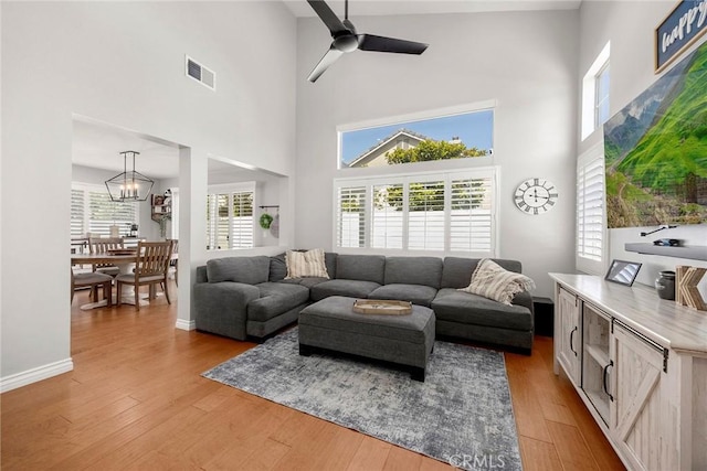 870 Clover Ln, Corona, CA 92878 - living room featuring a high ceiling, wood-type flooring, a chandelier, and a ceiling fan