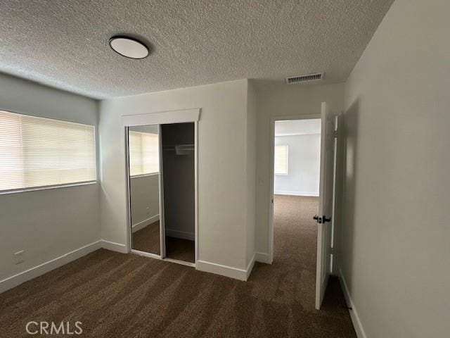 211-215 E California Ave, Ridgecrest, CA 93555 - unfurnished bedroom featuring a textured ceiling, dark carpet, and a closet