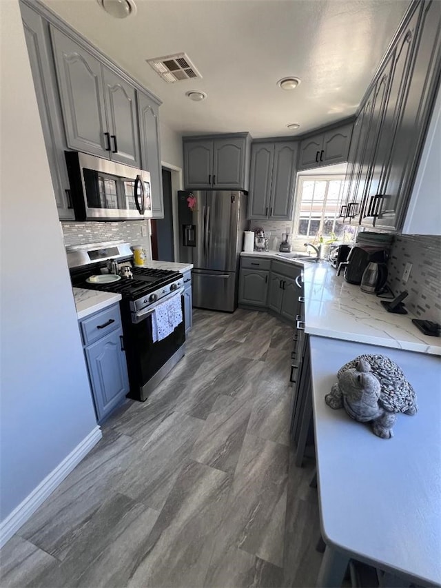 4552 Shasta Pl, El Monte, CA 91731 - kitchen with stainless steel appliances, backsplash, gray cabinets, and light stone countertops