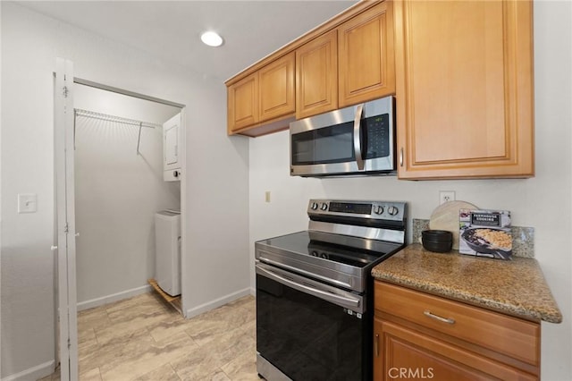 21981 Rimhurst Dr Unit 158, Lake Forest, CA 92630 - kitchen with stainless steel appliances, stacked washer / dryer, recessed lighting, brown cabinetry, and light stone counters