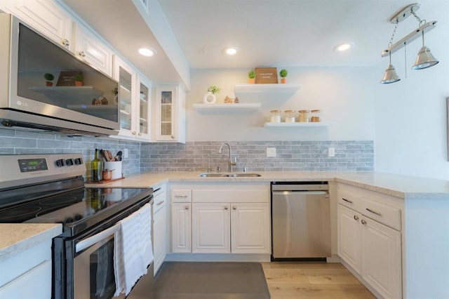 7083 Deerhurst Ct, San Diego, CA 92139 - kitchen with stainless steel appliances, open shelves, white cabinets, a peninsula, and light wood finished floors