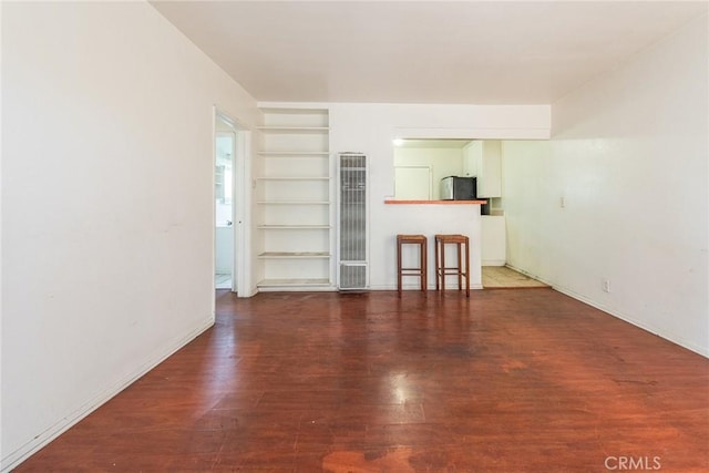 1132 E 65th St, Los Angeles, CA 90001 - unfurnished living room featuring a heating unit, built in shelves, and wood finished floors