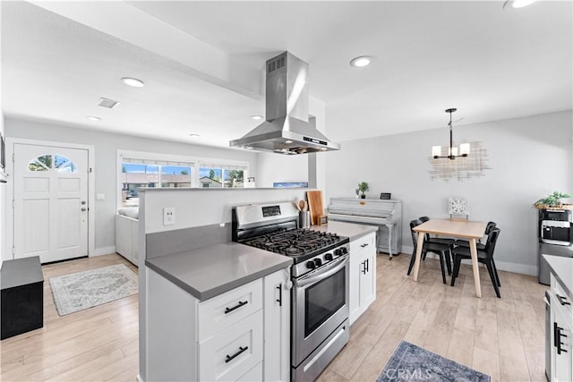 330 Glenshaw Dr, La Puente, CA 91744 - kitchen with stainless steel gas range, island range hood, light wood-style floors, white cabinetry, and a chandelier