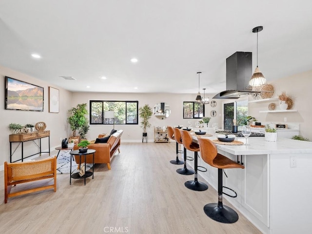971 N Clifford Ave, Rialto, CA 92376 - kitchen with island exhaust hood, light wood finished floors, recessed lighting, a kitchen bar, and decorative light fixtures