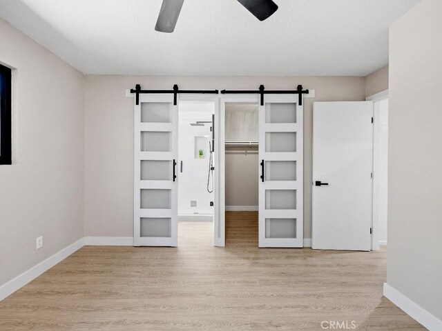 971 N Clifford Ave, Rialto, CA 92376 - unfurnished bedroom with a barn door, a spacious closet, wood finished floors, and ceiling fan