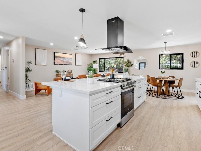 971 N Clifford Ave, Rialto, CA 92376 - kitchen with island exhaust hood, stainless steel range with gas cooktop, light wood-style floors, white cabinetry, and a center island