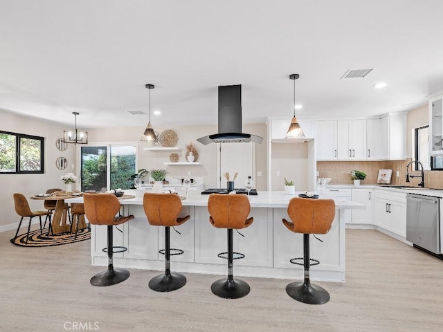 971 N Clifford Ave, Rialto, CA 92376 - kitchen featuring island range hood, stainless steel dishwasher, light wood-style flooring, white cabinets, and backsplash