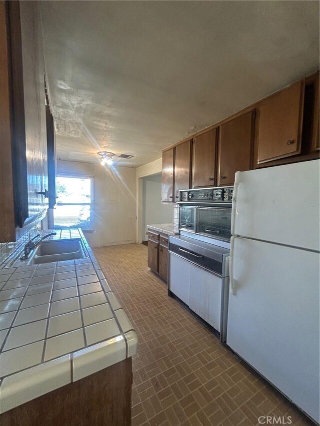 11818 Graystone, Norwalk, CA 90650 - kitchen featuring freestanding refrigerator, tile countertops, brick patterned flooring, and black oven