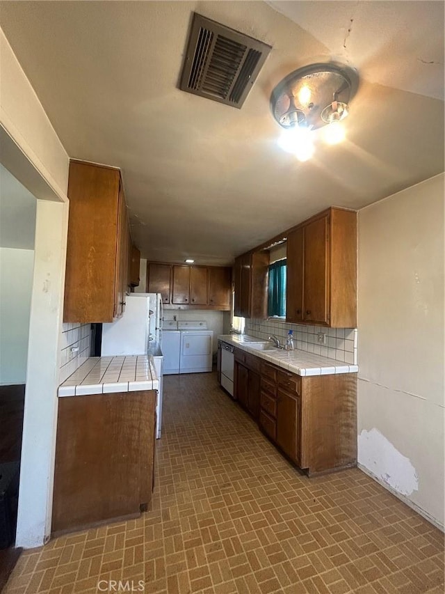 11818 Graystone, Norwalk, CA 90650 - kitchen with dishwashing machine, washer and clothes dryer, tile counters, backsplash, and brown cabinetry