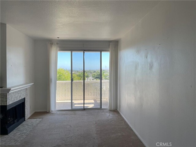 20331 Bluffside Cir Unit A320, Huntington Beach, CA 92646 - unfurnished living room with carpet, a tile fireplace, and a textured ceiling
