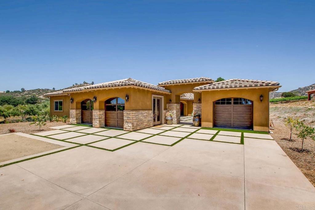 12087 Via Trevi, Lakeside, CA 92040 - mediterranean / spanish home featuring concrete driveway, a garage, stone siding, stucco siding, and a tiled roof