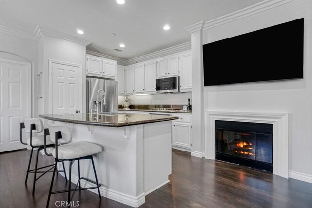 3393 Shadetree Way, Camarillo, CA 93012 - kitchen with appliances with stainless steel finishes, white cabinetry, dark wood-type flooring, a breakfast bar, and a center island with sink
