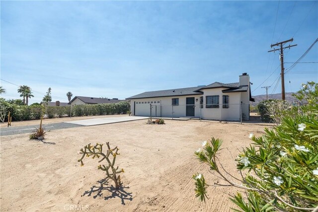 72011 Two Mile Rd Unit 29, Palms, CA 92277 - back of property featuring driveway, a garage, and a chimney