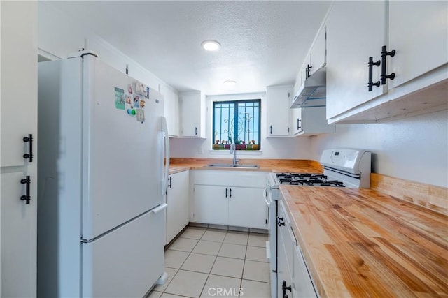 72011 Two Mile Rd Unit 29, Palms, CA 92277 - kitchen with white appliances, wooden counters, under cabinet range hood, white cabinetry, and light tile patterned floors