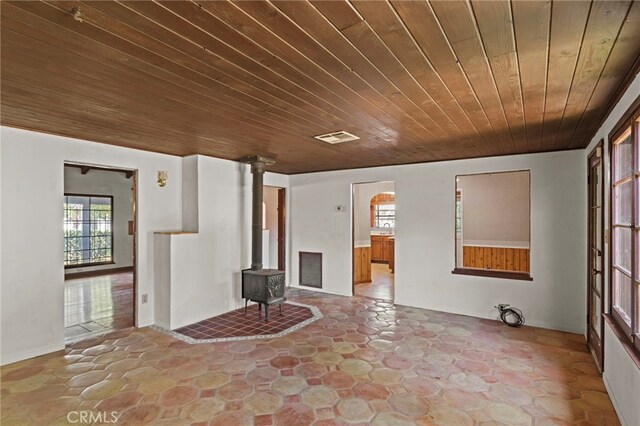 733 W 24th St, San Bernardino, CA 92405 - unfurnished living room featuring wood ceiling, a wood stove, arched walkways, and stone finish floors