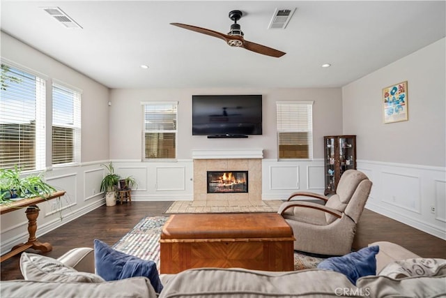 43145 62nd St W, Lancaster, CA 93536 - living room featuring wood finished floors, ceiling fan, a decorative wall, a tiled fireplace, and wainscoting