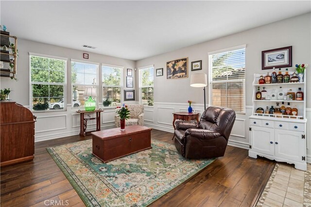 43145 62nd St W, Lancaster, CA 93536 - living area featuring dark wood-style flooring, a decorative wall, a wainscoted wall, and healthy amount of natural light