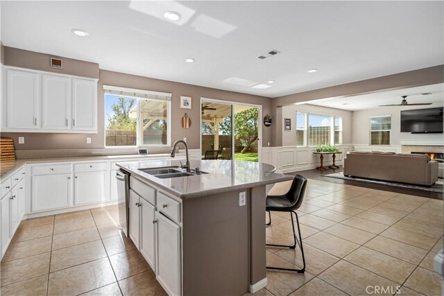 43145 62nd St W, Lancaster, CA 93536 - kitchen with light tile patterned floors, stainless steel dishwasher, open floor plan, white cabinetry, and an island with sink