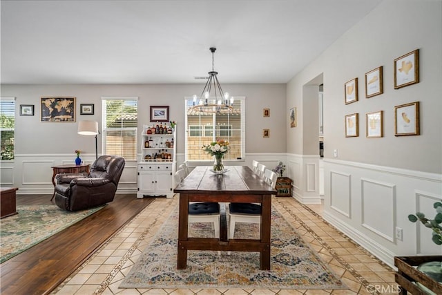 43145 62nd St W, Lancaster, CA 93536 - dining room featuring a chandelier, a wainscoted wall, a decorative wall, and light wood-style flooring